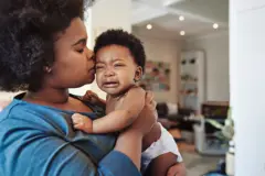 Enfant qui pleure dans les bras de sa maman