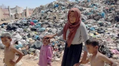 سيدة فلسطينية وثلاثة أطفال يقفون أمام تل من القمامة