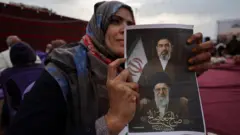 Žena drži fotografiju na kojoj se nalaze otac i sin Hamnei, Ali i Modžtaba