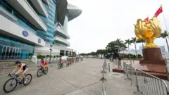 全运会香港赛区铁人三项测试赛上，单车手骑车从旁经过金紫荆广场