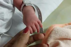 갓 태어난 아기의 손가락을 잡고 있는 모습