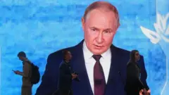 Люди проходять повз екран із зображенням Володимира Путіна на Міжнародному економічному форумі в Санкт-Петербурзі, 3 червня 2026 року.
