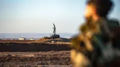 مقاتلون من قوات سوريا الديمقراطية يقفون حراسًا أمام رادار مهجور في مطار القامشلي الدولي، والذي كان في السابق قاعدة عسكرية سورية روسية مشتركة، في مدينة القامشلي شمال شرق سوريا 