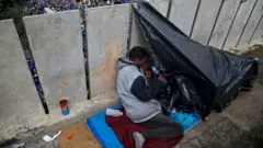 Um morador de rua senta-se em sua barraca improvisada em São Paulo, em 30 de maio de 2024.