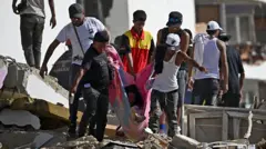 Grupo de pessoas transporta uma mulher em uma manta entre os escombros de um prédio de apartamentos danificado após um terremoto em Catia La Mar, estado de La Guaira, Venezuela.