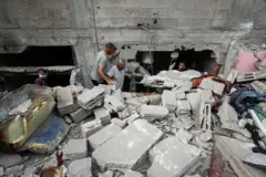 فلسطينيون يبحثون عن ضحايا في موقع غارة إسرائيلية ليلية على منزل في مدينة غزة، 6 يوليو/تموز 2025.