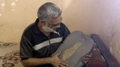 ضياء وهو يحمل بين بيديه حقيبة ابنه المدرسية