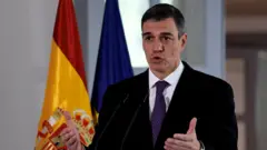 O primeiro-ministro espanhol, Pedro Sánchez, fala em frente à bandeira da Espanha