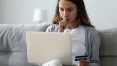 Mulher sentada no sofá usando laptop