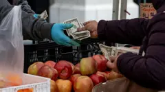 Pessoa pagando com cédulas de dólar em uma feira livre