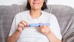 سيدة تمسك بيدها حقنة إنقاص الوزن