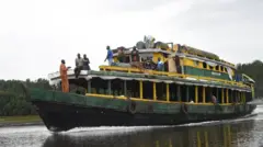 A big passenger boat wit some pipo standing on top di deck for Akuku Tori district of Rivers State, Nigeria