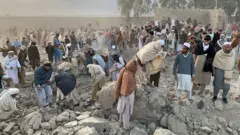 گروهی از مردان در حال جستجو در میان ویرانه‌های برجای مانده از حملات هوایی پاکستان بر منزل مسکونی 