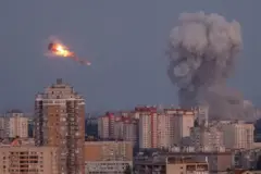 Kiev'de binaların üzerinden dumanlar yükseliyor ve havada bir füze alev almış halde görülüyor