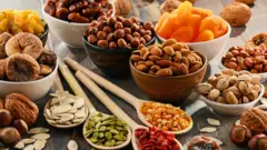 Mesa com potes de damasco e outras frutas secas e algumas oleaginosas como amêndoas e castanhas