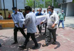 Familiares carregam os restos mortais de vítima do acidente aéreo da Air India