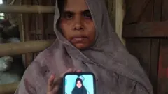 Sharifa Khatun holds up a telephone showing an image of a missing family member