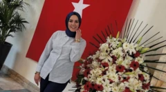 Saliha Akkaş TBMM'de Türk bayrağı ve bir çelengin önünde poz veriyor