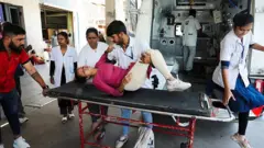Uma jovem em uma maca ao lado de uma ambulância é atendida por paramédicos após desmaiar devido ao calor intenso em Ahmedabad, na Índia.