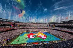Una toma amplia del estadio con un escenario colorido en el centro y la palabra "love" (amor) escrita en medio.