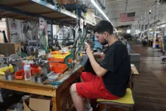 法蘭克·博特略（Frank Botelho）坐在機器前，正在加工扣件，這些扣件將用於他任職公司 Vanson Leathers 所製作的摩托車皮衣。