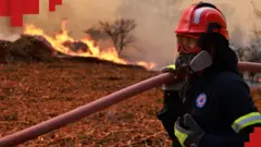 Пожежник на тлі пожежі у Греції
