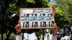 Mão segurando cartaz com fotos de Uribe