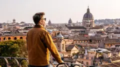 Um homem debruçado na borda de uma varanda em Roma.