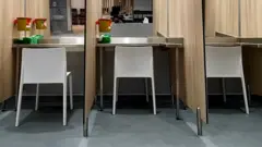 Close up of three booths, with white chairs against a mirrored back wall