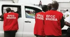 Àwọn èèyàn mẹ́ta tó wọ aṣọ pupa tí wọ́n kọ EFCC sẹ́yìn rẹ̀, wọ́n kọ ẹ̀yìn sí ẹ̀rọ ayàwòrán