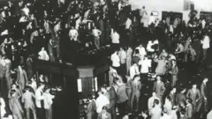Varias decenas de comisionistas de bolsa están parados con expresión de preocupación.
