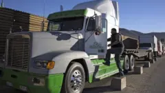 Un hombre subiendo a un camióngrand spin slotcarga en la frontera entre México y EE.UU.