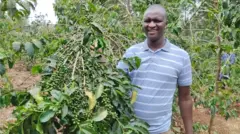 Martin Kinyua tenant une grappe de café.