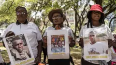 Родственники кенийских граждан, призванных в российскую армию в Украине, позируют с фотографиями своих близких во время молитвы и мирной демонстрации с требованием принять срочные меры по репатриации их родственников, Найроби, 19 февраля 2026 года.