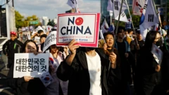 Un hombre, una mujer y otras personas que participan en la protesta sostienen pancartas con el lema "No a China".