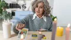 Starsza wróżka kładzie karty tarota na stole w domu