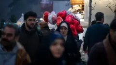 Um vendedor carrega balões em forma de coração perto de um santuário sagrado no norte de Teerã, Irã, em 13 de fevereiro de 2025, véspera do Dia dos Namorados.