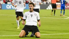 حمزة عبد الكريم - بملابس منتخب مصر قميص أبيض سروال أسود رقم 9 - يحتفل جاثياً على ركبتيه في الملعب في كأس العالم للشباب دون 17 عاماً