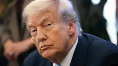 Fotografia do rosto de Trump no Salão Oval. Ele veste terno escuro e gravata azul.