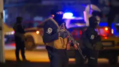 Genel Güvenlik Kuvvetleri personeli Lazkiye kentine konuşlandırıldı, üç personel biri odakta, diğerleri odak dışı, gece. 