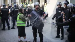 Studentkinja sa policajcem koji drži štit na ulici