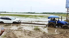 పొలాల్లో కూరుకుపోయిన కార్లను ట్రాక్టర్లతో బయటికి తీసుకొస్తున్నారు
