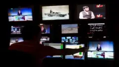 تصویری از کنترول رووم یک رسانه در افغانستان. اسکرین‌های زیادی از برنامه‌های مختلف و یک اپراتور در تصویر دیده می‌شوند.