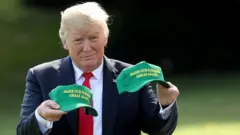 Trump mostra dois bonés no estilo MAGA, com os dizeres 'Make Our Farmers Great Again' ('Tornar os nossos agricultores grandes novamente').