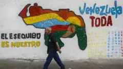 Un hombre pasa por un mural del mapa de Venezuela que incluye el Esequibo y al lado se lee: el Esequibo es nuestro.
