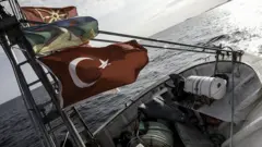 Filodaki gemilerden birinin ön kısmında Türk bayrağı dalgalanıyor.