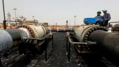 طاقم إصلاح سوداني يعمل في منشأة هجليج النفطية، بعد أن استأنف السودان ضخ النفط من الحقل النفطي المتضرر جراء الحرب في 2 مايو/أيار 2012، بعد 12 يومًا من مغادرة قوات جنوب السودان المحتلة للمنطقة.