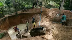 Una mina de diamantes informal en Sierra Leona, donde unos hombres tamizan en busca de gemas en un gran estanque,