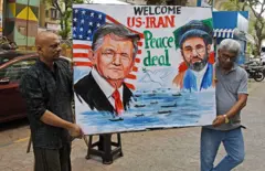 Dois homens carregando um desenho com a imagem de Trump e do líder supremo do Irã, Mojtaba Khamenei, com os dizeres: "Welcome US-Iran Peace Deal"