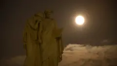 Uma Lua redonda e brilhante aparece em um céu escuro, atrás do Monumento à Paz no Capitólio dos EUA, em Washington, D.C